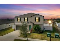 Charming two-story home with a well-manicured lawn, neutral paint, and a teal front door at 3059 Nubbin Ridge Ln, Zephyrhills, FL 33540