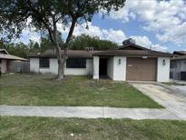 Modest single-story home with a brown roof, a front yard, and an attached one car garage at 12812 1St Isle, Hudson, FL 34667