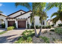 Beautiful home with a paver driveway, two car garage, and lush tropical landscaping at 17014 Clear Cork Dr, Wimauma, FL 33598