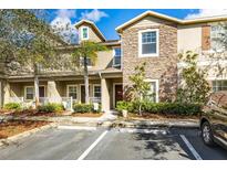 Charming townhouse featuring a stone facade, well-maintained landscaping, and convenient parking at 31211 Gossamer Way, Wesley Chapel, FL 33543