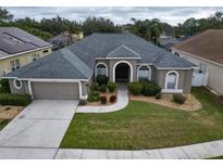 Inviting single-story home featuring a well-manicured lawn and a symmetrical facade with arched entryway at 5206 Whispering Leaf Trl, Valrico, FL 33596