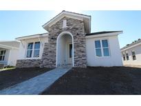 Charming single-story home with stone accents and a welcoming arched entrance on a sunny day at 687 Allora Ave, Nokomis, FL 34275