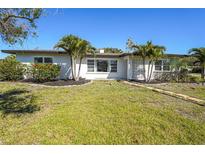 Charming single-story home featuring a lush green lawn and tropical palm trees in the front yard at 1309 Nokomis S Ave, Venice, FL 34285