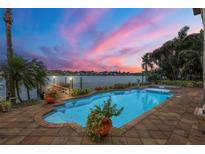 Inviting waterfront pool with brick surround and beautiful sunset views over the water at 1097 Eden Isle Ne Dr, St Petersburg, FL 33704