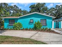 Charming, bright blue one-story home with beautiful landscaping, decorative window boxes, and a concrete driveway at 717 Carolina Ave, Tarpon Springs, FL 34689