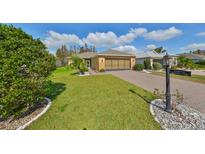 Charming single-story home with a well-manicured lawn and a brick driveway, situated in a tranquil neighborhood at 1123 Emerald Dunes Dr, Sun City Center, FL 33573
