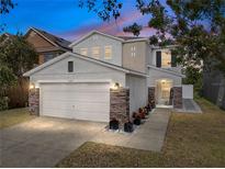 Charming two-story home featuring a two-car garage and stone accents at twilight at 6324 Magnolia Trails Ln, Gibsonton, FL 33534