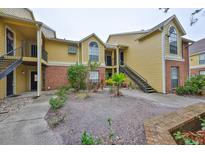 Yellow condo building featuring brick accents and landscaped courtyard at 8609 Mallard Reserve Dr # 103, Tampa, FL 33614