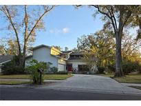Charming home with a red front door, mature trees, long driveway and a well-manicured front lawn at 1735 Tall Pine Cir, Safety Harbor, FL 34695