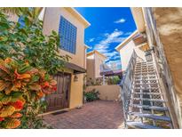 Charming courtyard entrance featuring brick pavers, tropical landscaping, and stairs leading to upper levels at 487 Pinellas Bayway S # 205, Tierra Verde, FL 33715