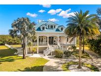 Stunning two-story home with white facade, blue roof, and tropical landscaping at 6785 Burning Tree Dr, Seminole, FL 33777