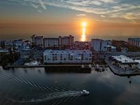 Stunning aerial view of waterfront condos at sunset with a boat cruising by, tennis courts and calm waters at 18325 Gulf Blvd # 405, Redington Shores, FL 33708