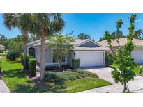 Charming single-story home with a two-car garage, well-manicured lawn, and lush landscaping at 15856 Cobble Mill Dr, Wimauma, FL 33598