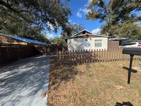 Charming home featuring a cozy front yard with a picket fence and a paved driveway at 8014 N Alaska St, Tampa, FL 33604