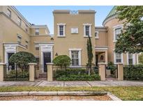 Elegant townhome featuring a manicured front yard with a wrought iron fence and tasteful landscaping at 2419 Victoria Gardens Ln, Tampa, FL 33609