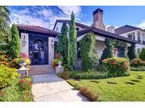 Elegant stone home with an inviting gated entrance, lush landscaping, and a stone chimney at 200 Brightwaters Ne Blvd, St Petersburg, FL 33704