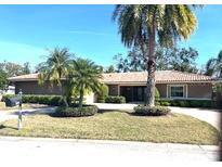 Charming single story home with lush landscaping, a terracotta roof, and mature palm trees at 2450 Roberta Ln, Clearwater, FL 33764