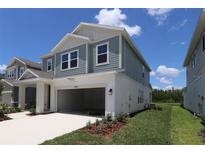 Two-story home featuring a two-car garage and blue siding against a clear, sunny sky at 28965 Orange Berry Dr, Wesley Chapel, FL 33543