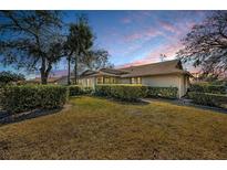 Beautiful single-story home with well-manicured lawn and mature trees under a colorful sunset sky at 9204 Golf View Dr, New Port Richey, FL 34655