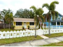 Inviting yellow home with pineapple-themed picket fence, palm trees, and sidewalk leading to the front door at 2526 44Th S St, St Petersburg, FL 33711