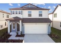 Two-story home featuring a two-car garage, well-manicured landscaping, and large front porch at 1149 Kistna Dr, Zephyrhills, FL 33540