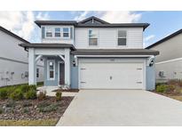 Charming two-story home featuring a two-car garage and manicured landscaping at 1165 Kistna Dr, Zephyrhills, FL 33540