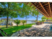 Charming backyard patio with lush landscaping and a serene view of the lake and dock perfect for relaxing outdoors at 10532 94Th Pl, Seminole, FL 33772