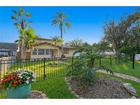 Charming home with lush landscaping, palm trees, and a wrought iron fence at 156 29Th N Ave, St Petersburg, FL 33704