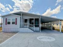 Charming single-story home with a covered carport and a decorative manatee design on the driveway at 206 S Port Royal Ln, Apollo Beach, FL 33572