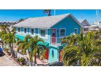 Charming turquoise two-story home with red door, white trim, and lush tropical landscaping near the marina at 308 2Nd St N # 202, Bradenton Beach, FL 34217
