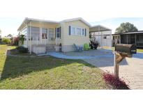 Charming manufactured home featuring colorful Adirondack chairs and lush lawn at 114 W Saint Johns Way, Apollo Beach, FL 33572