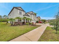 Charming two-story home features tropical landscaping, a well-manicured lawn, and a long driveway at 5045 Ivory Stone Dr, Wimauma, FL 33598