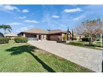 Charming one-story home featuring a paved driveway, manicured lawn, screened porch, and beautiful landscaping at 1228 Caloosa Creek Ct, Sun City Center, FL 33573