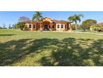 Beautiful single-story home featuring a sprawling lawn, mature trees, and a welcoming facade with a grand entrance at 14739 Vista View Ct, Dade City, FL 33523