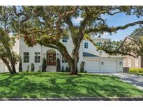 Stately two-story white home featuring a well-manicured lawn and three-car garage at 4614 W Tennyson Ave, Tampa, FL 33629
