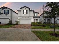 Charming two-story home with neutral colors, attached garage, and brick paver driveway at 7491 Notched Pine Bnd, Wesley Chapel, FL 33545