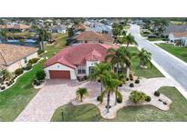 Stunning aerial view of a home with a red tile roof, palm trees, and a brick driveway at 1115 Signature Dr, Sun City Center, FL 33573