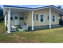Charming yellow single-Gathering home featuring a covered front porch with ample seating at 35020 Colony Hills Dr, Zephyrhills, FL 33541