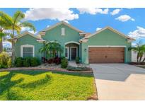 Charming one-story home featuring a lush front yard with tropical landscaping and a two-car garage at 13911 Artesa Bell Dr, Riverview, FL 33579