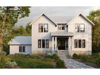 Charming two-story home with a metal roof, stone foundation, lush landscaping, and an inviting front porch at 515 Bosphorous Ave, Tampa, FL 33606