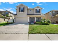 Charming two-story home with a well-manicured lawn, covered entryway, and two-car garage at 7718 Landcare Ln, Tampa, FL 33616