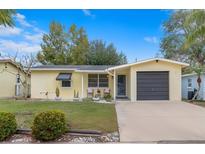Charming single-story home with a well-maintained lawn, neutral paint, attached garage, and inviting front porch at 1230 7Th Ne Ave, Largo, FL 33770