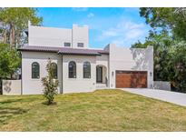 Charming two-story home with a tile roof, manicured lawn, and a driveway leading to a wooden garage door at 1802 E Park Cir, Tampa, FL 33610
