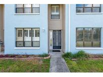 Charming light blue townhouse with a secure, decorative front door and a well-maintained walkway and landscaped garden at 1849 Abrico Dr # 4, Lutz, FL 33558