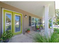 Inviting front porch with rocking chairs and a vibrant green door, complemented by lush greenery at 12261 Eldon Dr, Largo, FL 33774