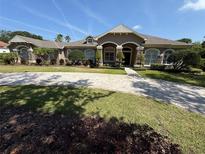 Charming single-story home featuring an arched entrance, manicured landscaping, and a spacious brick driveway at 8503 Kentucky Derby Dr, Odessa, FL 33556