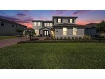 Beautiful home showcasing fresh landscaping, a brick driveway, and elegant exterior lighting at 7721 Roma Dune Dr, Wesley Chapel, FL 33545