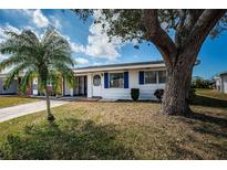 Charming single-story home boasts a well-maintained front yard with mature trees and vibrant blue shutters at 10022 Lily N St # N, Pinellas Park, FL 33782
