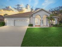 Charming single-story home features a well-manicured lawn, a three-car garage, and a welcoming arched entryway at 1545 Deerbourne Dr, Wesley Chapel, FL 33543
