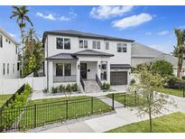 Beautiful two-story home with a manicured lawn, black metal fence, and paved driveway at 242 Estado Ne Way, St Petersburg, FL 33704